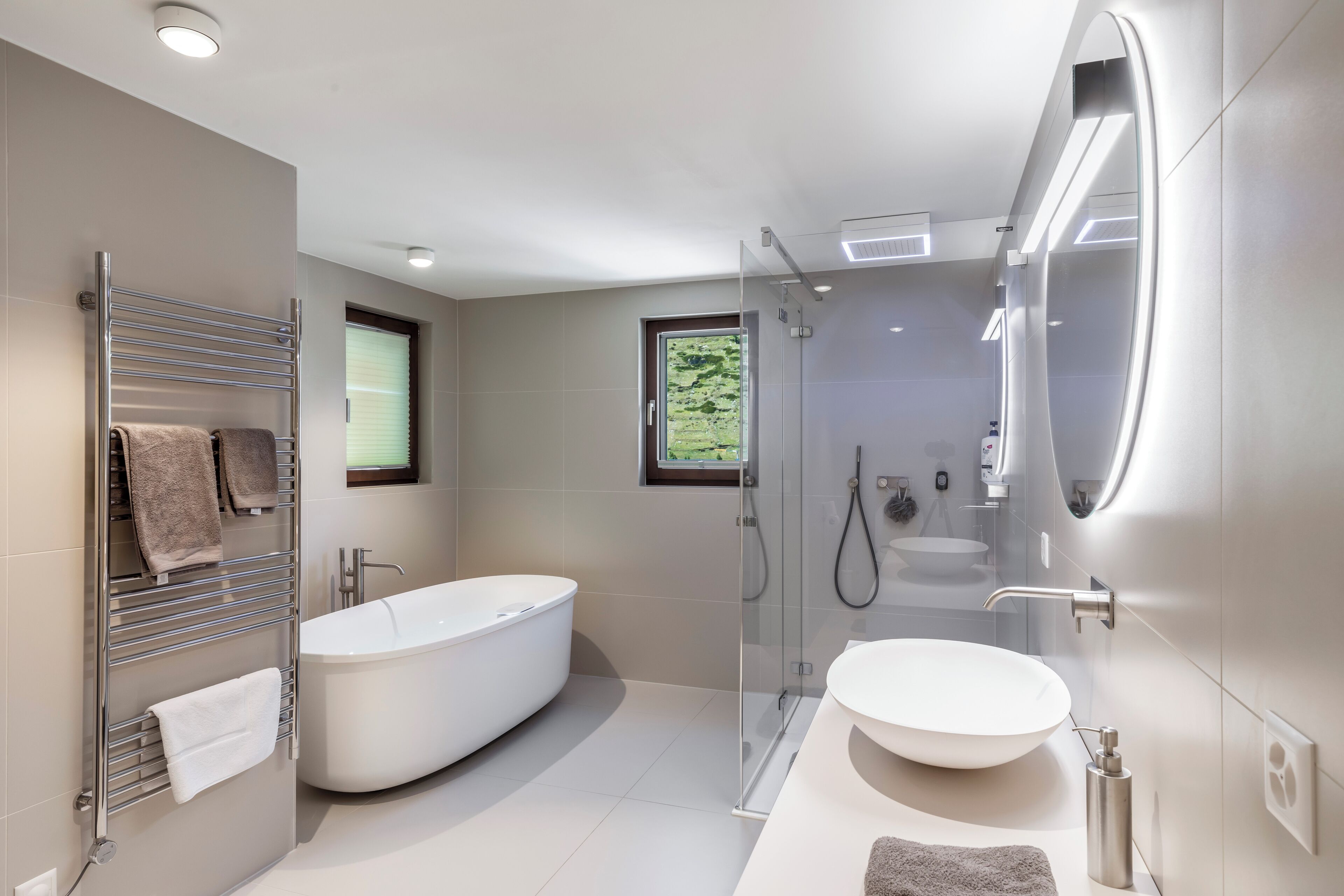 A modern bathroom with a freestanding bathtub, a glass-enclosed shower, and a large mirror.