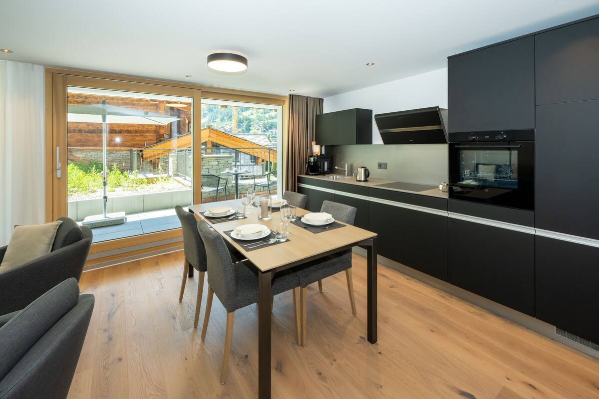 A modern kitchen with a built-in oven and a dining area with a table set for four.