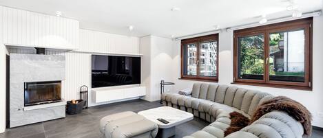A modern living room with a fireplace, a large sectional sofa, and a flat-screen TV.