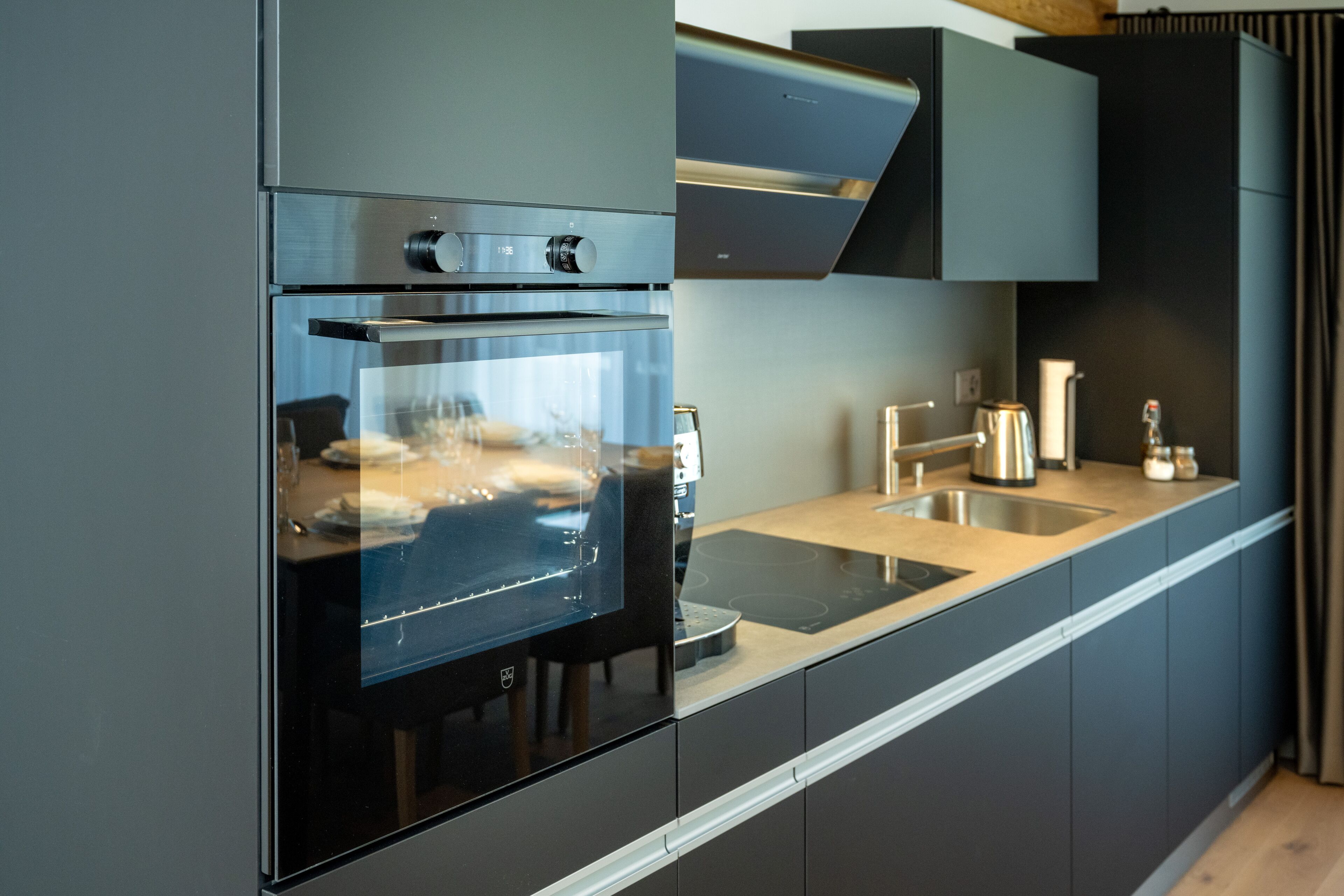 A modern kitchen with a built-in oven, stainless steel countertops, and a sleek backsplash.