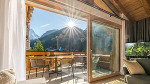 A balcony with a mountain view, wooden furniture, and a television. - Luxury Residence Colosseo Zermatt (Zermatt)