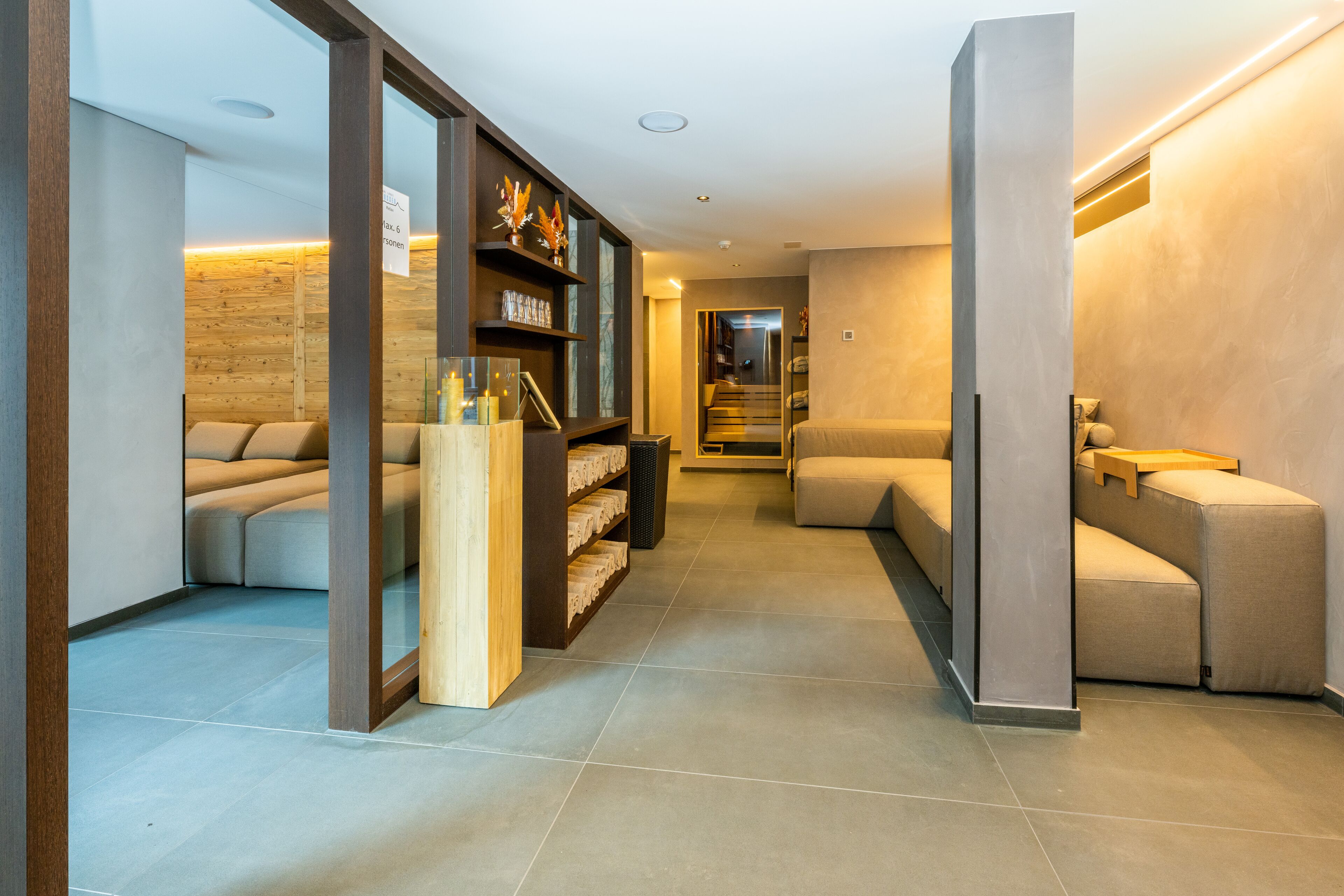 A modern interior with a sofa, a wooden bookshelf, and a staircase leading to another level.