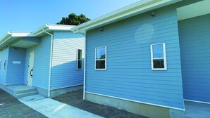 Uma fileira de casas azuis térreas, com detalhes em branco, cada uma com uma pequena janela e porta.