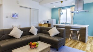 Uma sala de estar moderna com um sofá seccional, um espaço de cozinha pequeno e uma mesa de jantar.