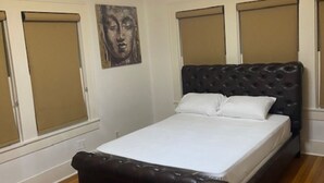 Un dormitorio con una cama, una lámpara en el techo y una ventana con persianas.
