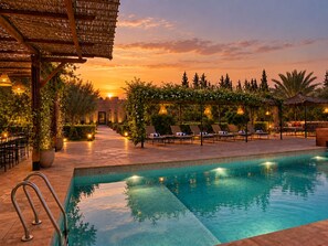 A poolside area with lounge chairs and a clear pool at sunset. - Villa Malaa'ika for 20 people (Marrakech)
