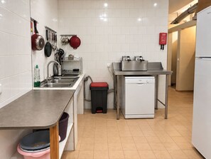 A modern kitchen with white tiles, stainless steel appliances, and a dishwasher.