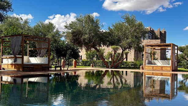 A serene pool area with two wooden gazebos and a castle-like structure in the background. - Villa Malaa'ika for 20 people (Marrakech)