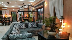 A modern living room with a sectional sofa, a glass coffee table, and decorative plants. - Villa Malaa'ika for 20 people (Marrakech)