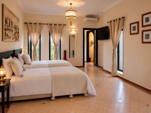 A hotel room with two beds, a large mirror, a flat-screen TV, and a painting on the wall. - Villa Malaa'ika for 20 people (Marrakech)