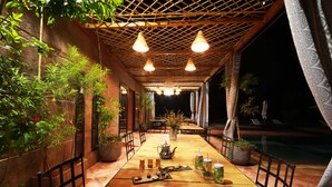 An outdoor dining area with a wooden table, chairs, and potted plants. - Villa Malaa'ika for 20 people (Marrakech)