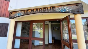 L'entrada de Le Marolles, amb un rètol de fusta, portes de vidre grans i una paret de pedra visible a l'interior.