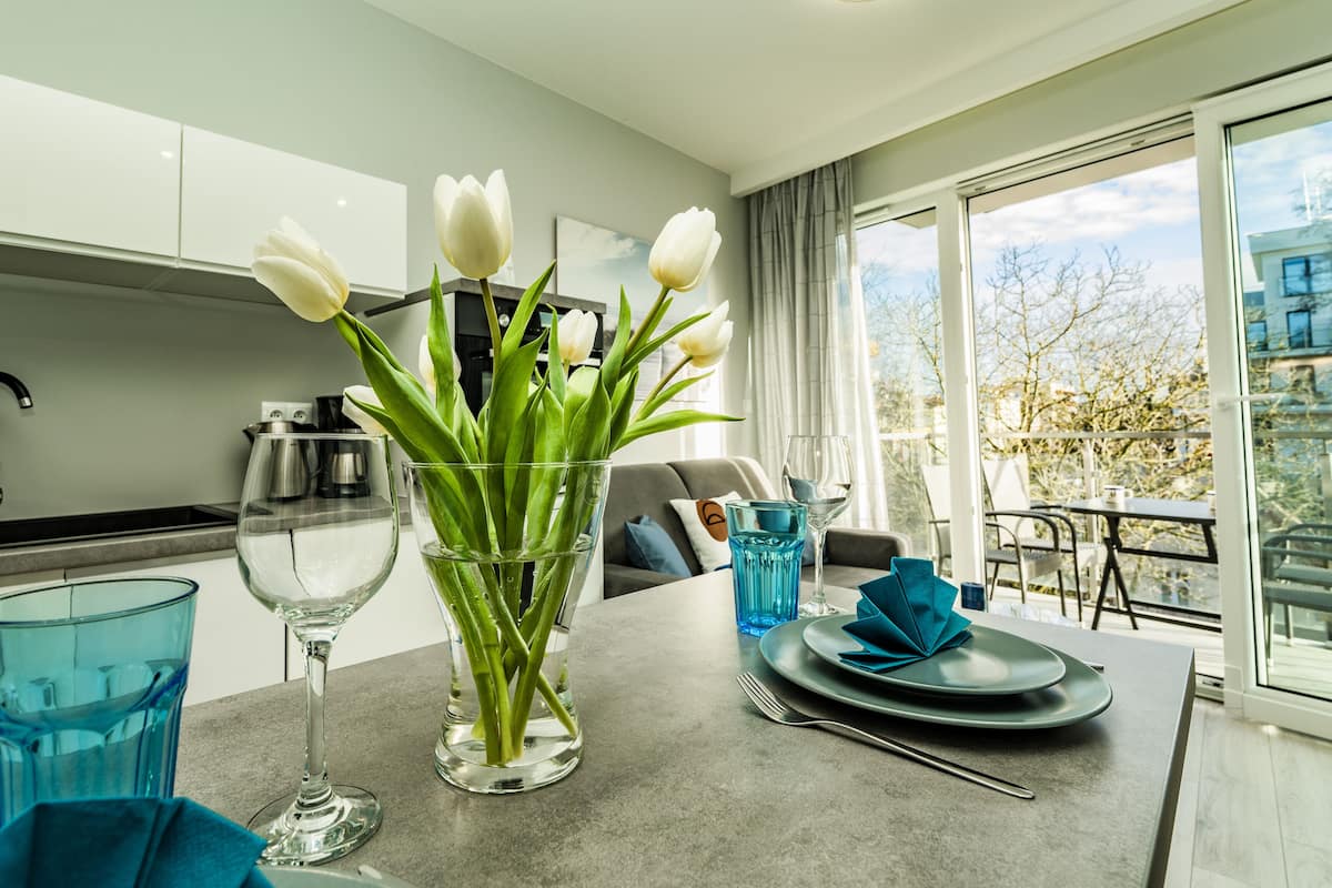 Een moderne keuken met een eethoek, een vaas met witte tulpen en uitzicht op de omgeving.