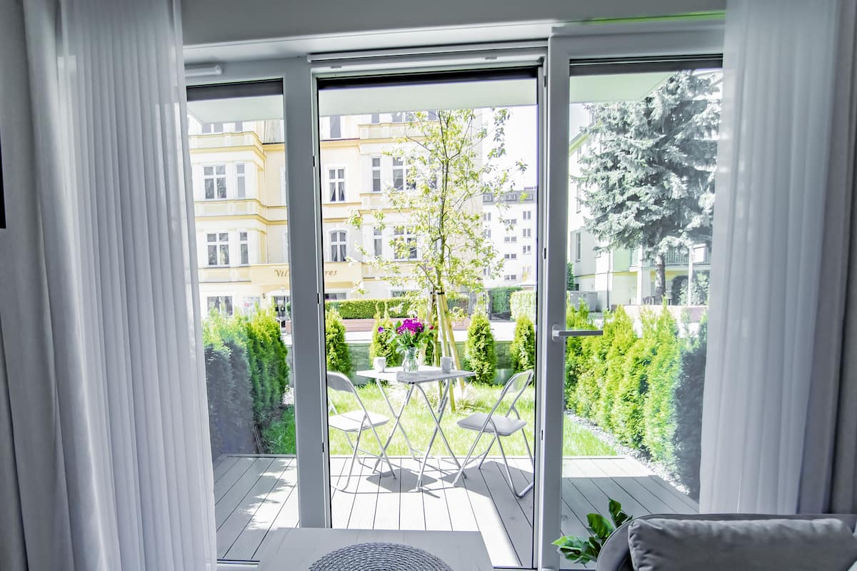 Een balkon met uitzicht op een tuin en gebouwen.