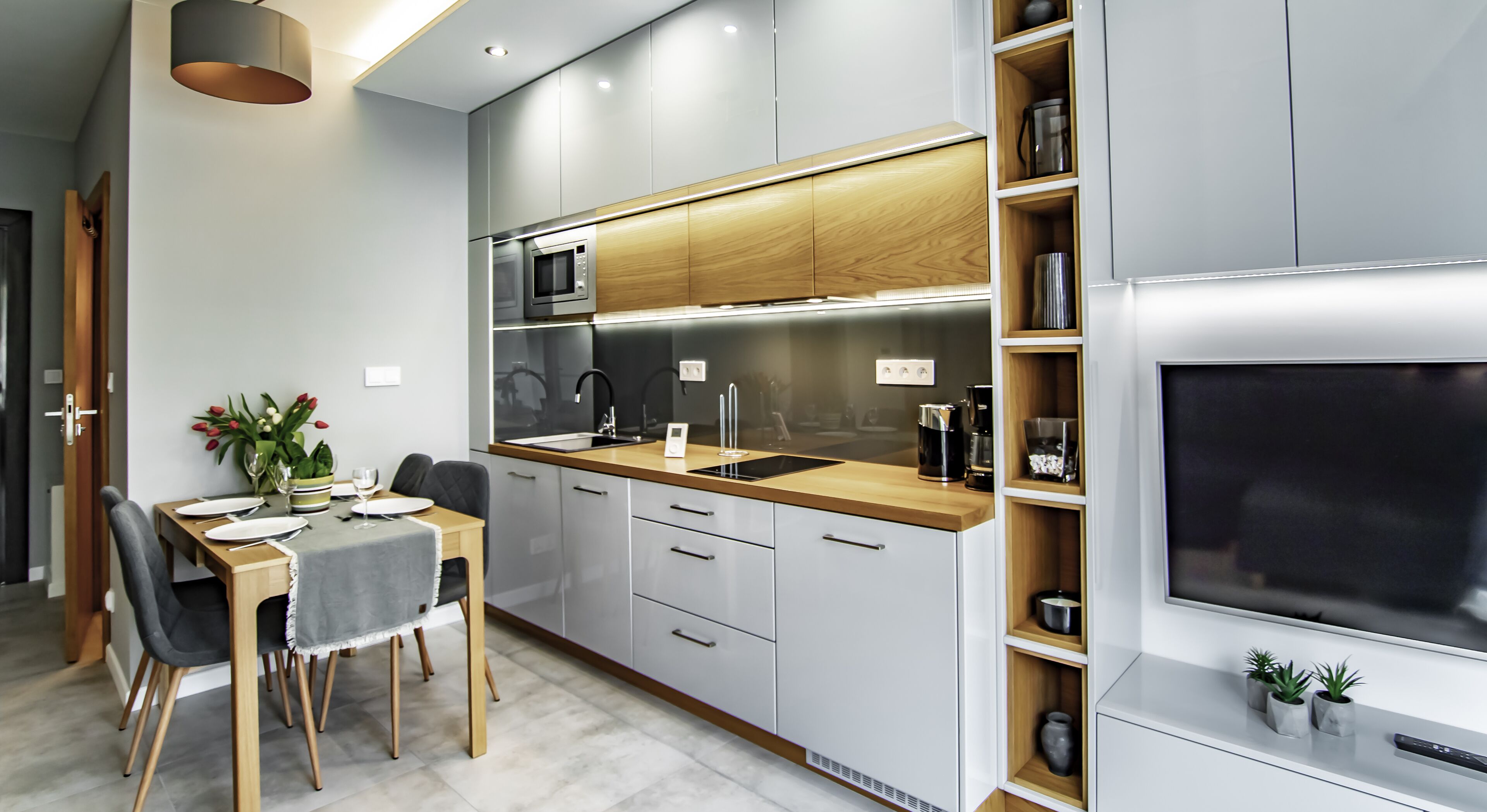 Een moderne keuken met een houten aanrechtblad, inbouwapparatuur en een eethoek met een tafel gedekt voor twee personen.