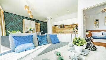 A modern living room with a sofa, dining table, and kitchen area.