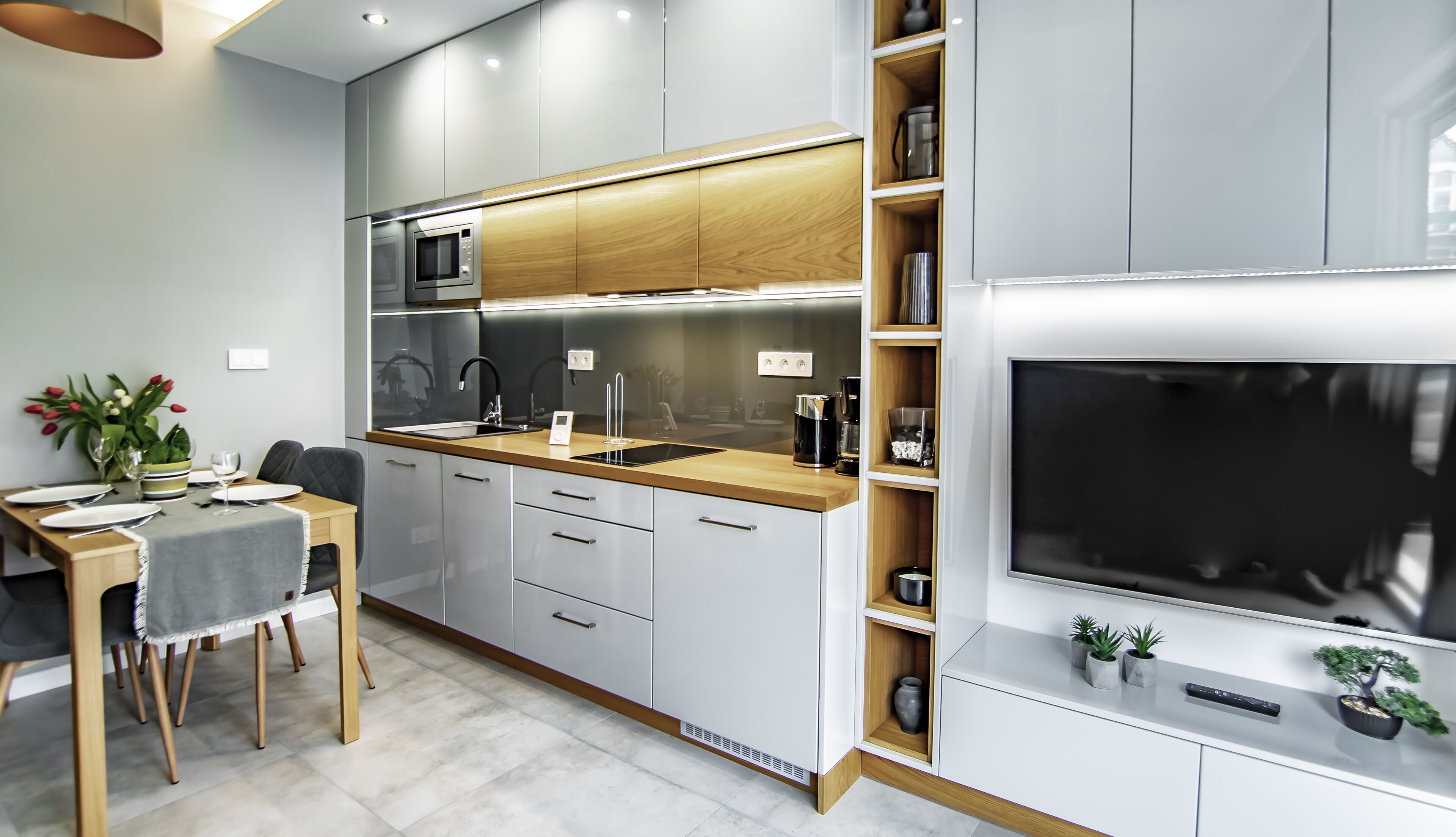 A modern kitchen with a built-in microwave, oven, and sink. There is a dining area with a table and chairs.