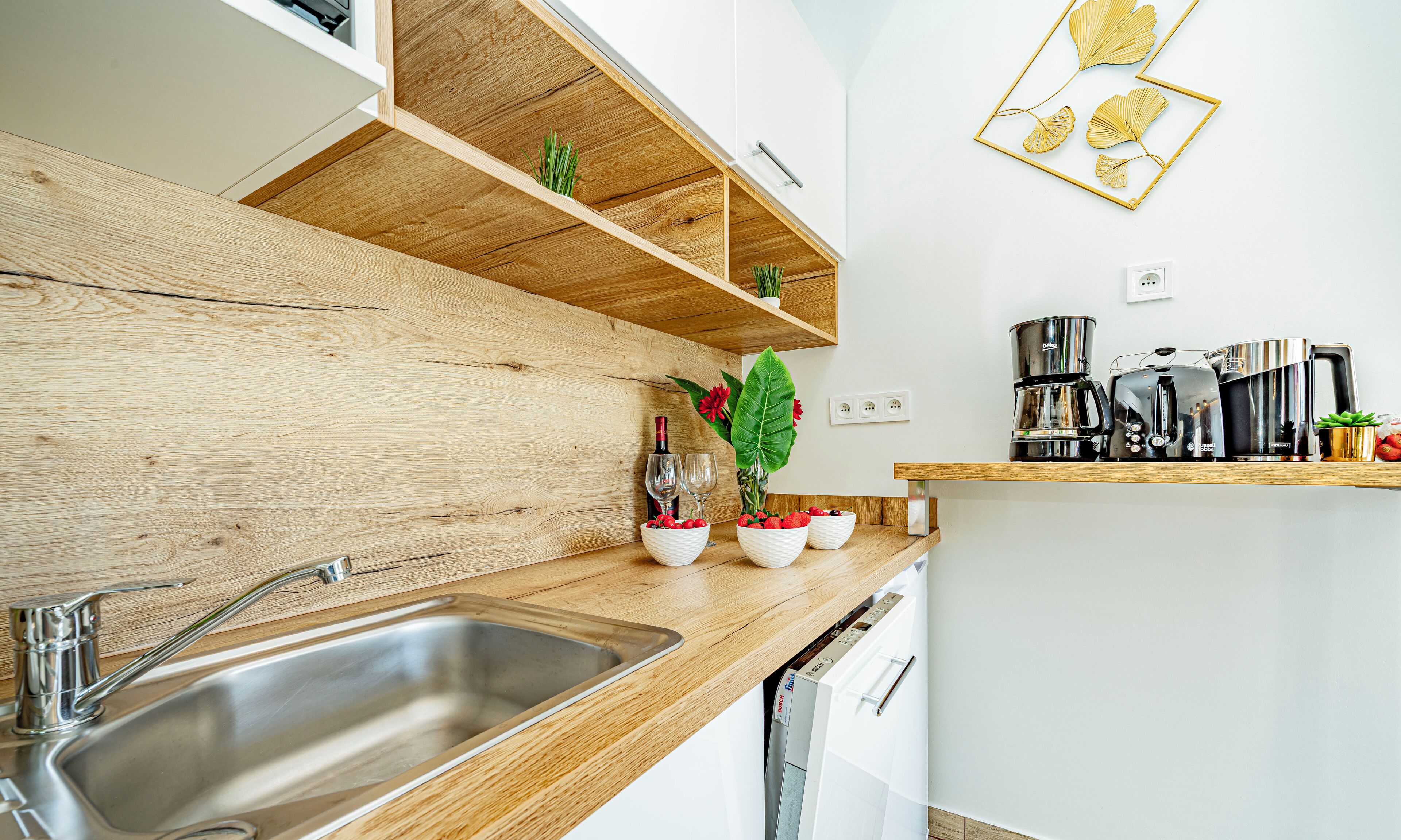Una cocina moderna con armarios de madera, un lavamanos de acero inoxidable y una máquina de café.