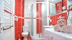 Ein Badezimmer mit Dusche, Toilette und Waschmaschine.