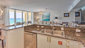 A modern kitchen with granite countertops, stainless steel appliances, and a large island with a sink. - Beachfront Fort Walton Beach Condo w/ Pool Access! (Fort Walton Beach)