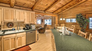 A log cabin interior with a kitchen, dining area, and a large window. - 11 Mi to Rainbow Lake: Family Home w/ Large Yard (Pinetop)