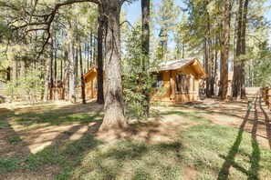 A cabin surrounded by tall pine trees in a forest setting. - 11 Mi to Rainbow Lake: Family Home w/ Large Yard (Pinetop)