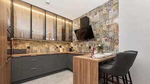 A modern kitchen with a wooden island, dark grey cabinets, and a patterned backsplash. - Stylish Apartment with Balcony | Parking | Close to the Oder River (Wroclaw)