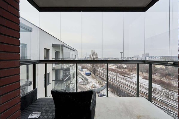A balcony with a view of a modern building and railway tracks.