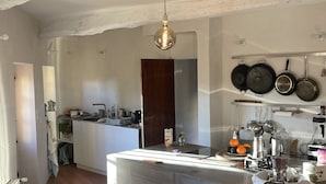 A modern kitchen with a central island, stainless steel appliances, and a hanging pot rack. - Village house with garden and pool (ANSOUIS)
