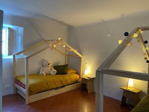 A child's bedroom with a wooden bed frame, a teddy bear, and string lights.