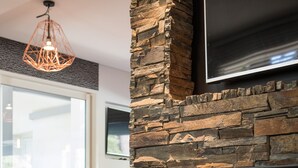 Ein modernes Interieur mit Steinwand, Kamin und schwarzen Stühlen.