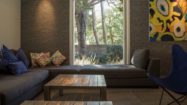 Ein modernes Wohnzimmer mit einem großen Fenster, einem Sofa, einem Couchtisch und einem blauen Sessel.