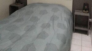 Ett sovrum med en säng, två sängbord och två tavlor som hänger på väggen.