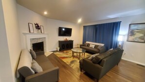 A modern living room with a fireplace, a flat-screen TV, and two sofas.