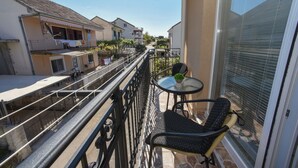 Un balcón con puerta de cristal, una mesita con una silla y vista a edificios cercanos.