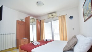 Una habitación de hotel con cama, armario, espejo, radiador y un reloj en la pared.