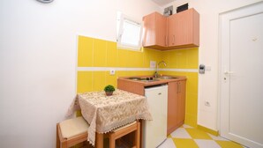 Una cocina compacta con un lavamanos, un refrigerador pequeño y una mesa con una planta.