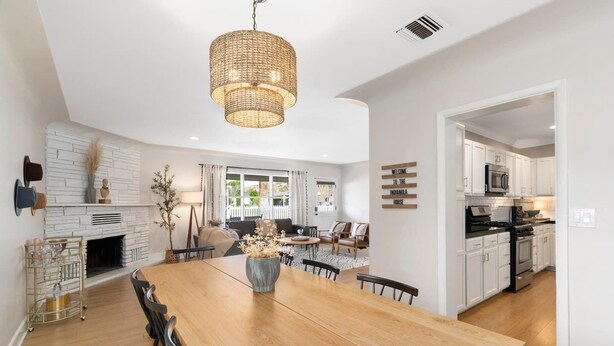 A spacious living area with a large wooden dining table, a fireplace, and a kitchen with white cabinets and modern appliances. - 4 bedrooms in one of the most popular + charming neighborhoods in Arcadia (Phoenix)
