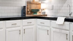 A kitchen with white cabinets, a black countertop, and a wooden backsplash. - 4 bedrooms in one of the most popular + charming neighborhoods in Arcadia (Phoenix)