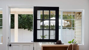 A room with a wooden desk, a white door, and a window with a view of a white fence and greenery. - 4 bedrooms in one of the most popular + charming neighborhoods in Arcadia (Phoenix)