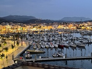 Marina con numerosas embarcaciones amarradas, rodeada de edificios y un paisaje montañoso.