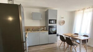 Una cocina moderna con gabinetes grises, microondas, horno y comedor con mesa y sillas de madera.