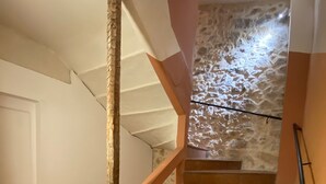Una escalera con barandales de madera y un muro de piedra al fondo.