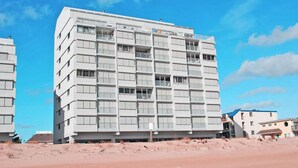 A multi-story hotel with a modern architectural design, featuring balconies and a flat roof. - Spacious, comfortable 2 bedroom oceanfront condo with free WiFi, an outdoor pool, and an enclosed balcony with a great ocean view located midtown only steps to the beach! (Ocean City)