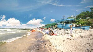Una playa con barcos, gente y cielo despejado.
