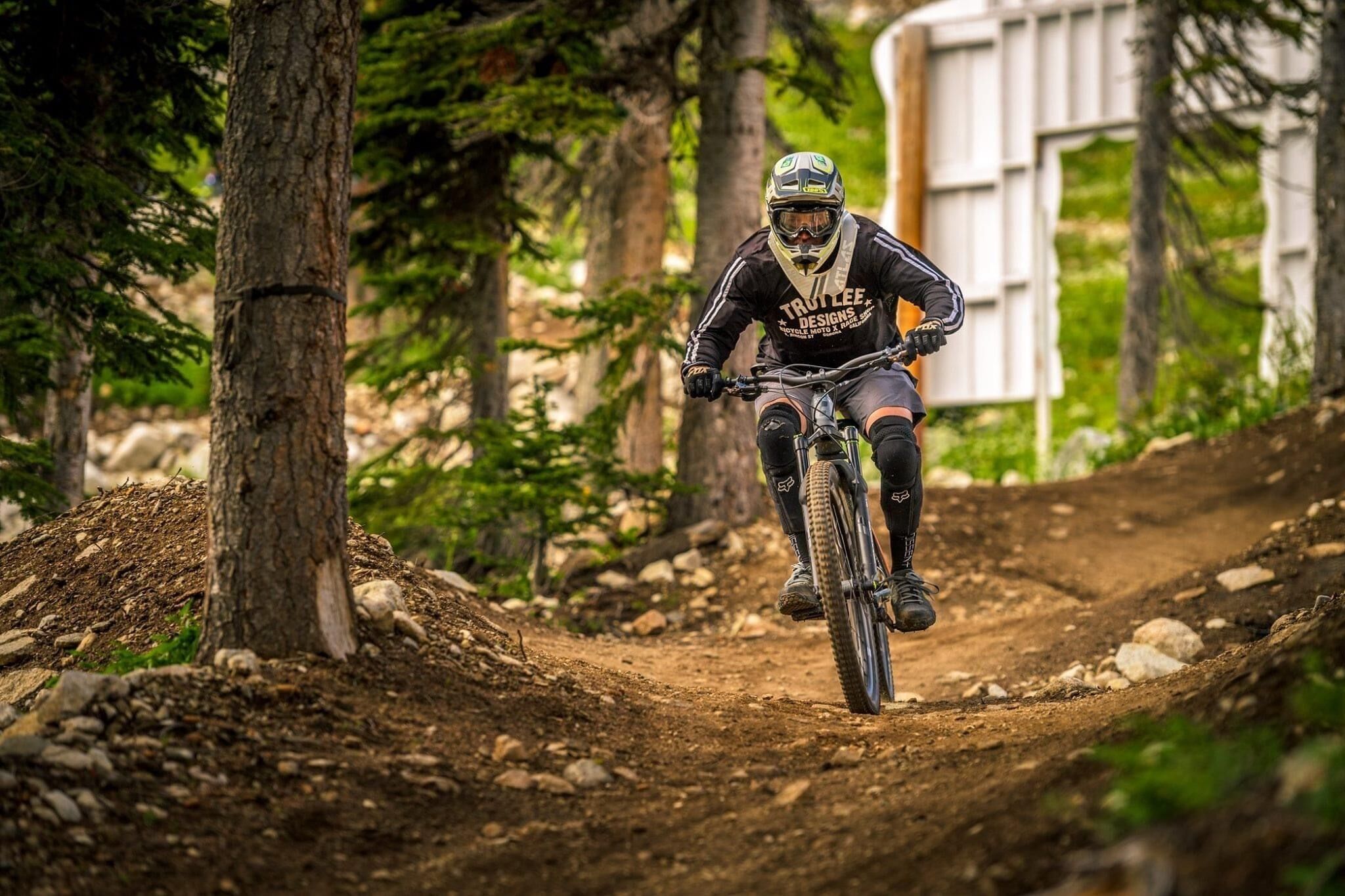 A mountain biker on a dirt trail surrounded by trees.