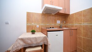 Une cuisine compacte équipée d’un réfrigérateur, d’un évier et d’une petite table agrémentée d’une plante.