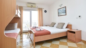 Une chambre à coucher avec un lit, une armoire en bois, une petite commode, une horloge et une fenêtre avec des rideaux.