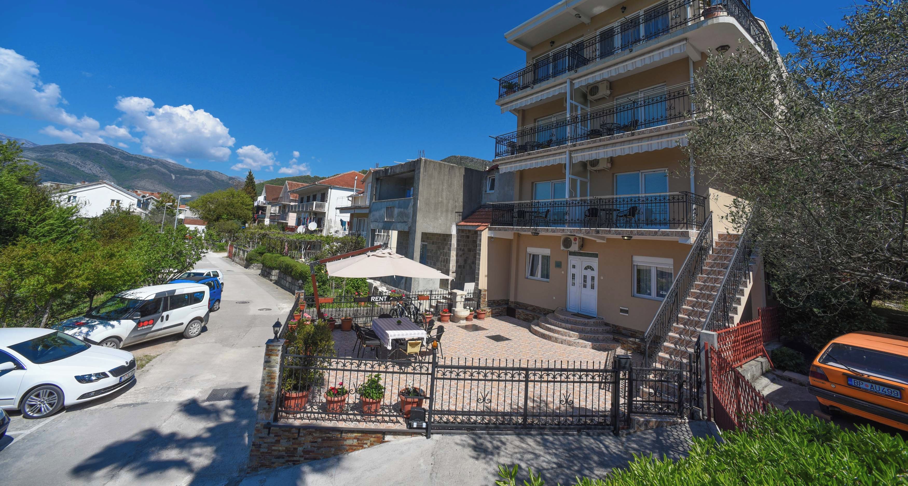 A multi-story building with balconies, a paved courtyard, and a view of the surrounding area.