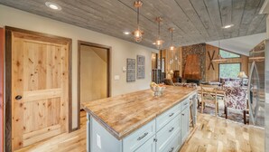 A spacious kitchen with a wooden island, pendant lighting, and a stone accent wall. - Gorgeous Rippling Waters!  Private Hot Tub- Spectacular Views! (Nathrop)